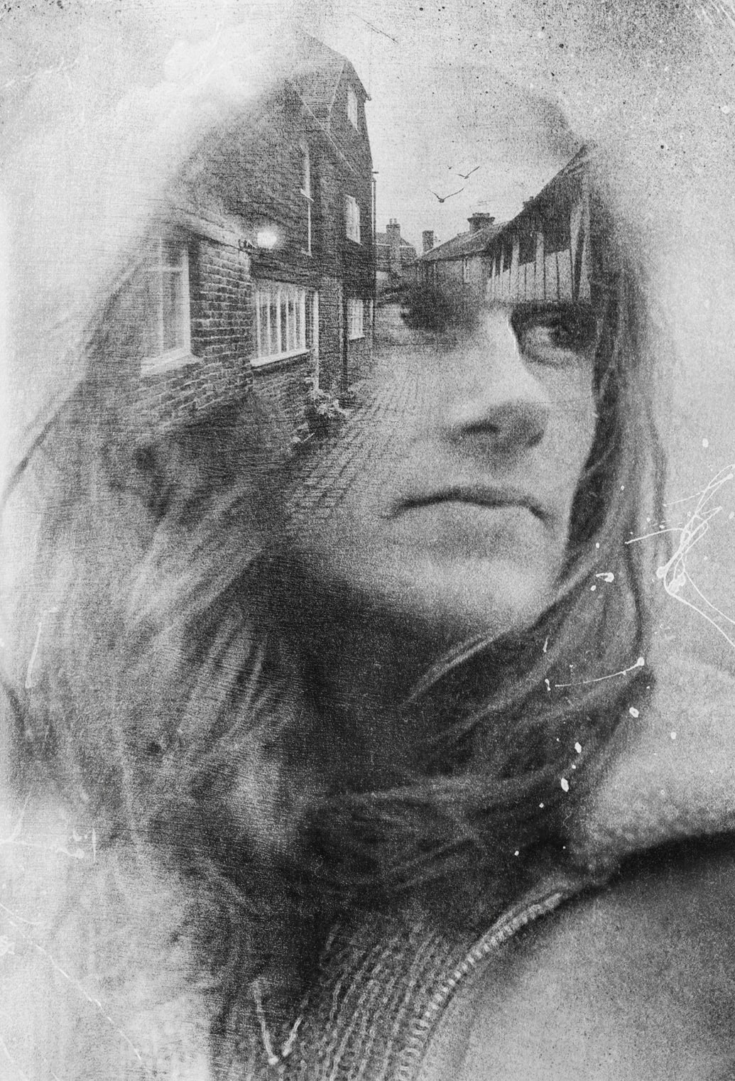 A black-and-white double exposure image showing a close-up of a pensive person with long hair, overlaid with a cobblestone street and old houses, creating a dreamy, vintage effect.